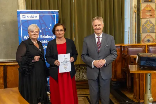 Wręczenie nagrody w Krakowie, trzy osoby pozujące z dyplomem.