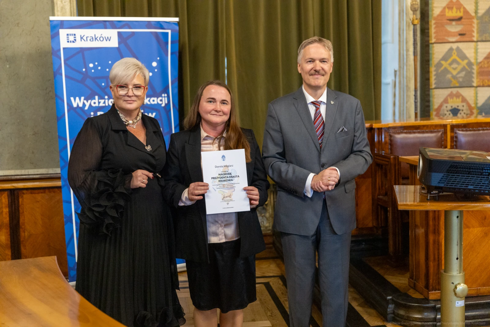 Wręczenie dyplomu w sali obrad, trzy osoby uśmiechają się do kamery.  Autor: Bogusław Świerzowski