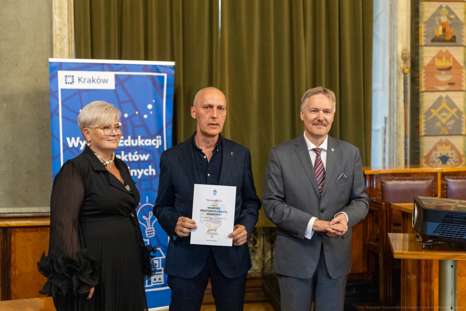 Wręczenie nagrody w Krakowie, trzej uczestnicy, dokument w rękach mężczyzny.  Autor: Bogusław Świerzowski