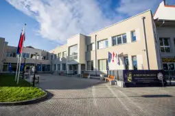 Budynek szkoły z flagami i banerem z okazji jubileuszu.