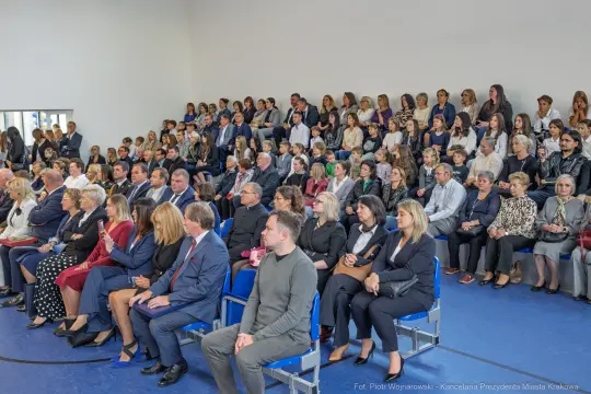 Tłum ludzi siedzących na widowni w sali, uczestniczących w wydarzeniu.