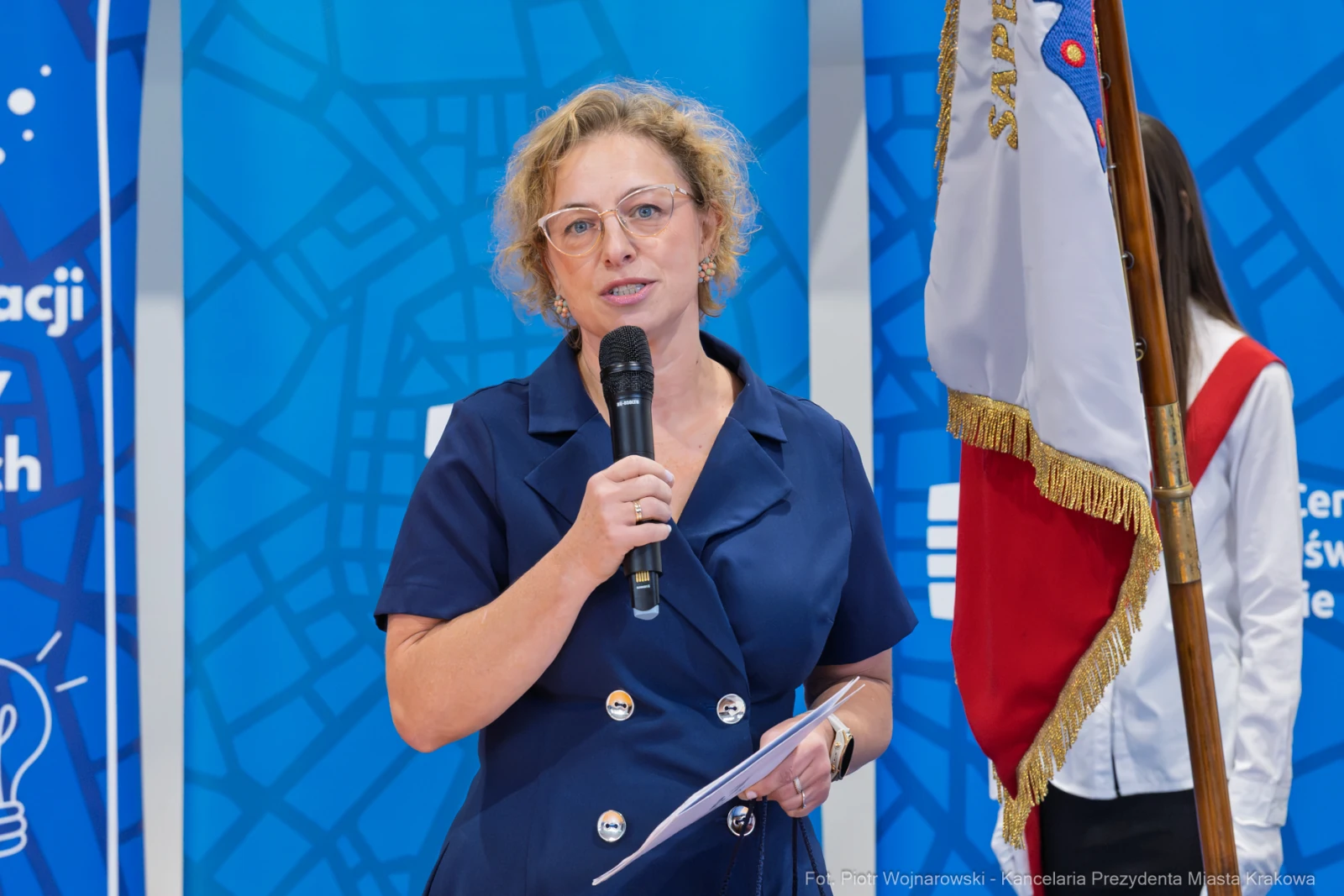 Kobieta z mikrofonem wygłasza przemówienie, obok stoi osoba z flagą.  Autor: Piotr Wojnarowski
