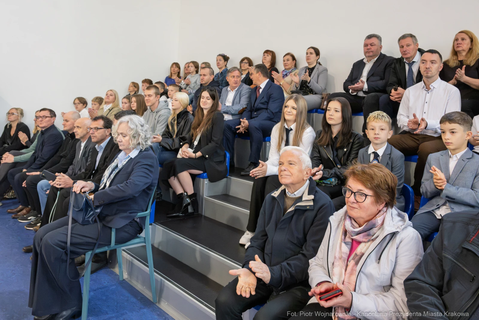 Grupa ludzi siedzących na widowni, niektórzy klaskają, w tle widać uśmiechy i eleganckie ubrania.  Autor: Piotr Wojnarowski