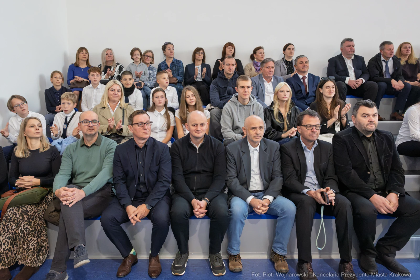 Grupa ludzi siedzących na trybunach, wśród nich dzieci i dorośli, w różnych strojach.  Autor: Piotr Wojnarowski