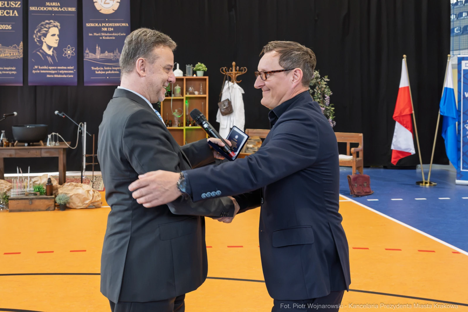 Dwaj mężczyźni w garniturach, uściski dłoni, mikrofon w ręku jednego z nich.  Autor: Piotr Wojnarowski