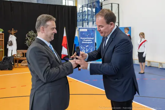 Wręczenie nagrody w trakcie uroczystości szkolnej z udziałem przedstawicieli władz.