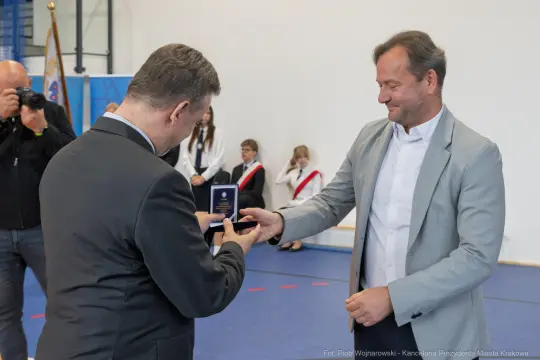 Wręczenie medalu podczas uroczystości w sali sportowej.