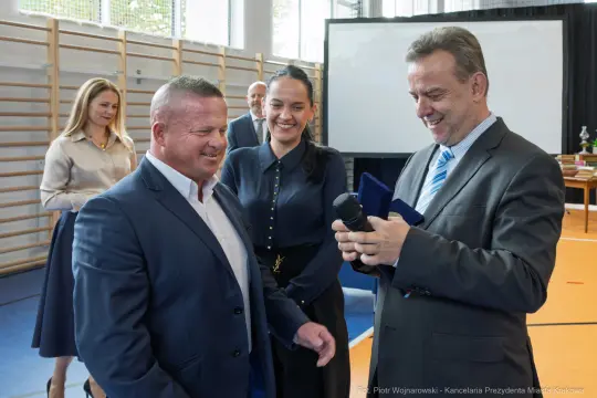 Wręczenie nagrody w uroczystej atmosferze, uśmiechy i gratulacje.