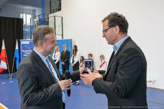 Wręczenie nagrody podczas uroczystości w hali sportowej.