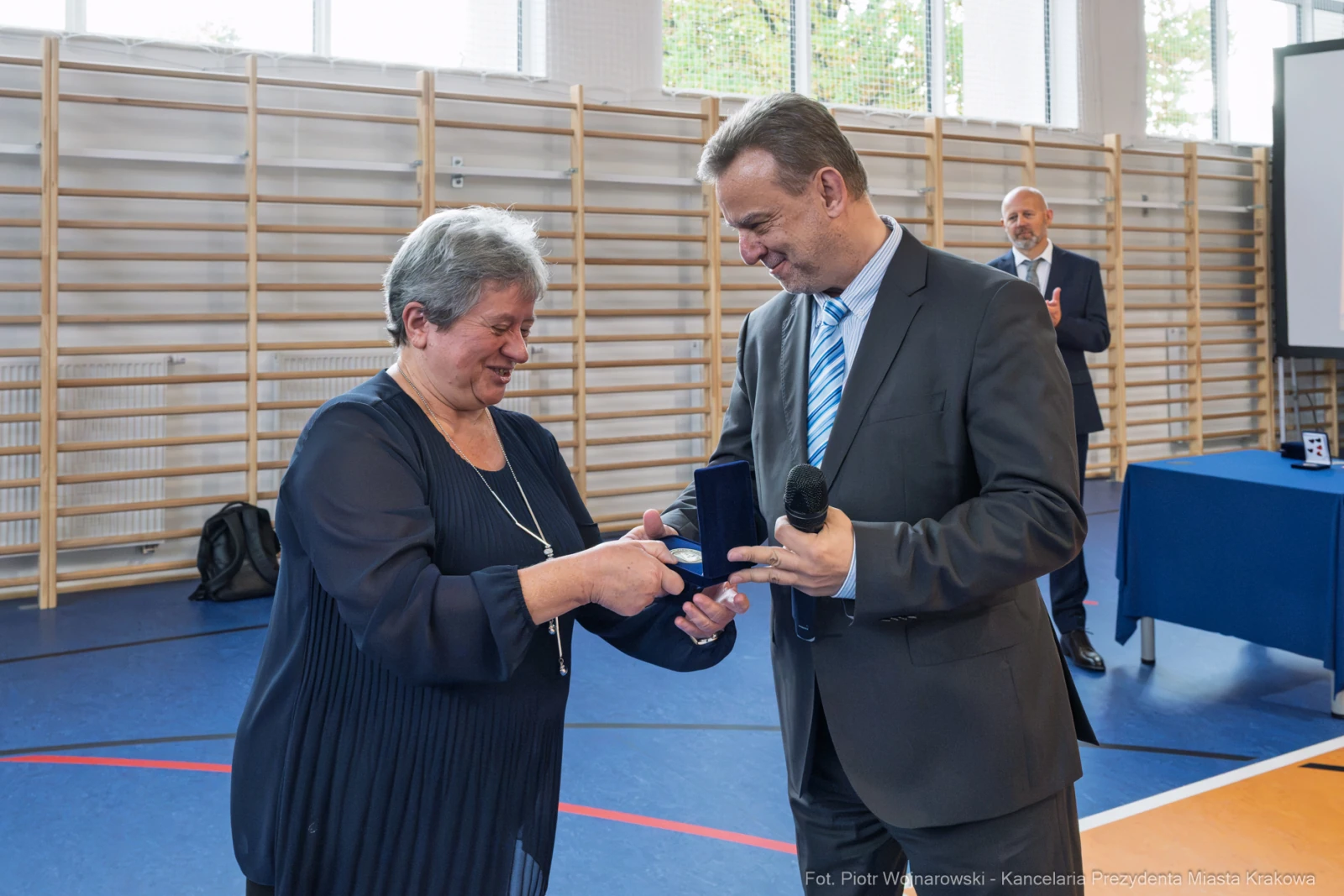 Wręczenie medalu przez mężczyznę kobiecie podczas uroczystości w hali sportowej.  Autor: Piotr Wojnarowski