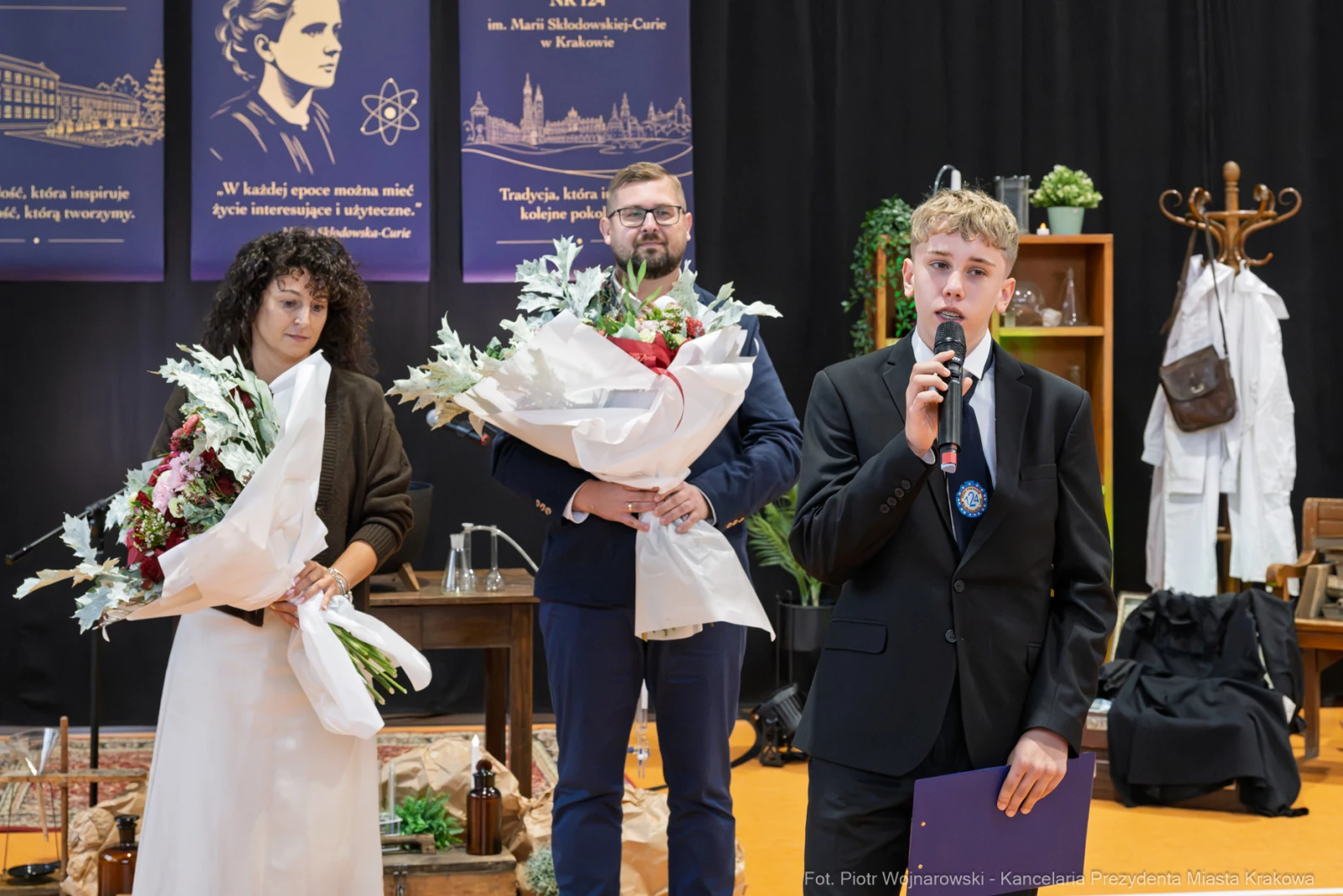 Uczestnicy ceremonii wręczenia nagród z kwiatami i mikrofonem.  Autor: Piotr Wojnarowski
