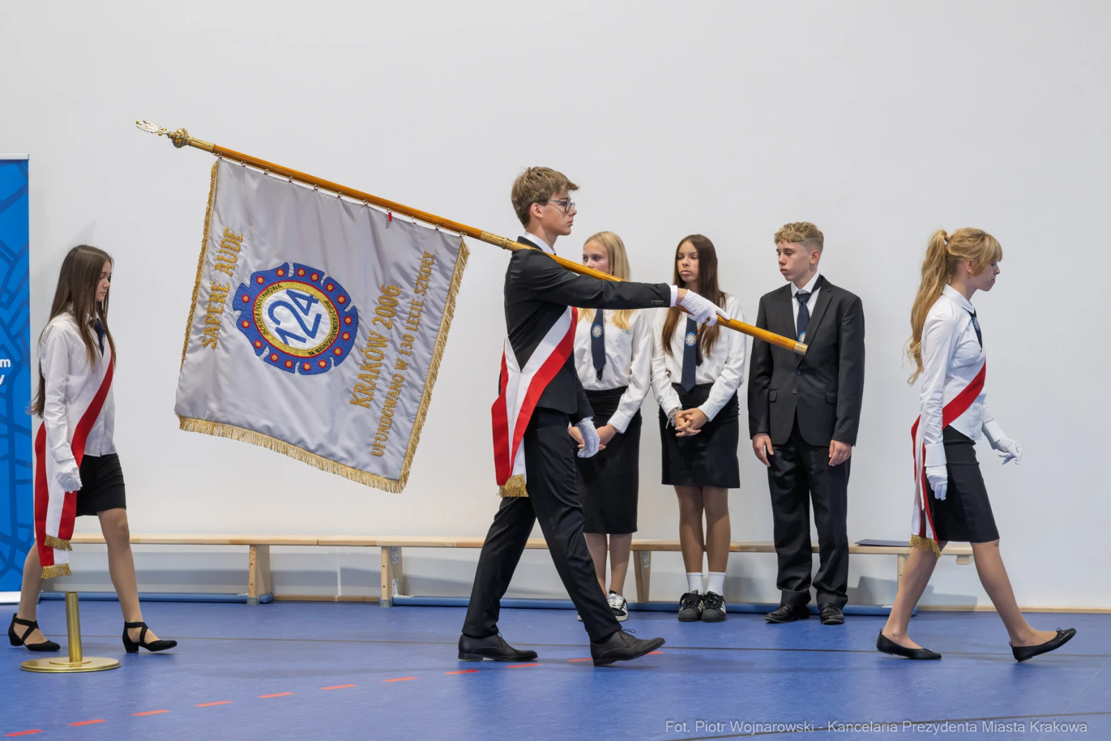 Uczniowie w strojach galowych podczas ceremonii z flagą i sztandarem.  Autor: Piotr Wojnarowski