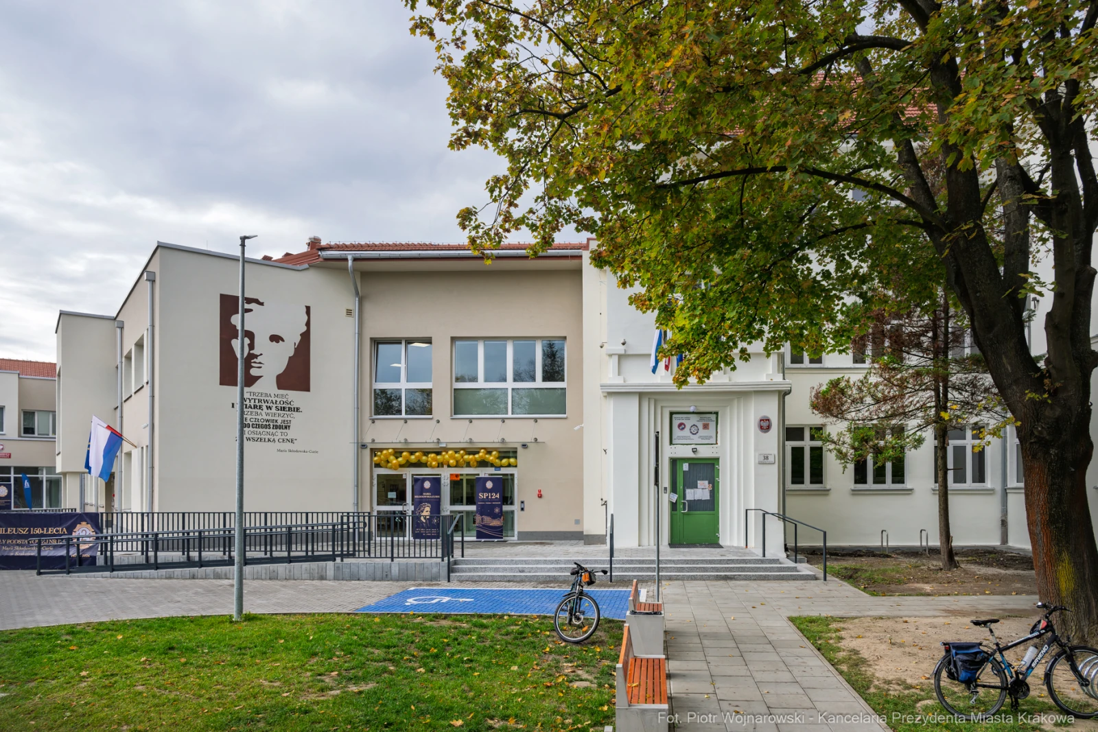 Budynek z muralem, drzwiami wejściowymi i rowerem na parkingu.  Autor: Piotr Wojnarowski