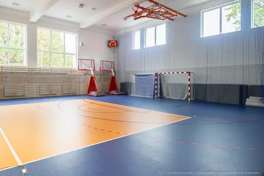 Pusta sala sportowa z boiskami do koszykówki i piłki ręcznej.