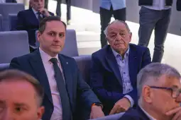 Dwaj mężczyźni siedzący obok siebie w eleganckim otoczeniu.