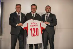 Trzech mężczyzn trzyma koszulkę z napisem Wisła Kraków i numerem 120.