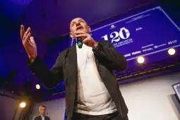 Mężczyzna z mikrofonem na scenie, gestykulujący podczas wystąpienia.