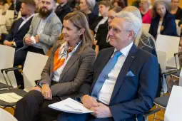 Uczestnicy konferencji siedzący na sali, uśmiechający się i rozmawiający.