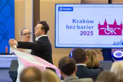 Para tańcząca w eleganckich strojach, z flagą w rękach, podczas wydarzenia Kraków bez barier 2025.