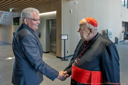 Spotkanie dwóch mężczyzn w formalnych strojach, uściski dłoni.