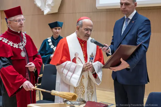 Ceremonia z udziałem duchownego, wręczenie dokumentu, tradycyjne stroje.