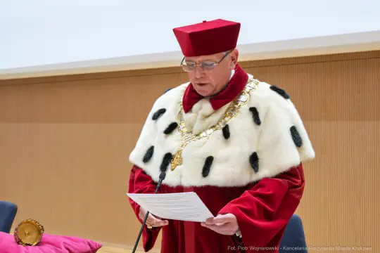 Mężczyzna w czerwonym birecie i płaszczu z futrem, czyta dokument.