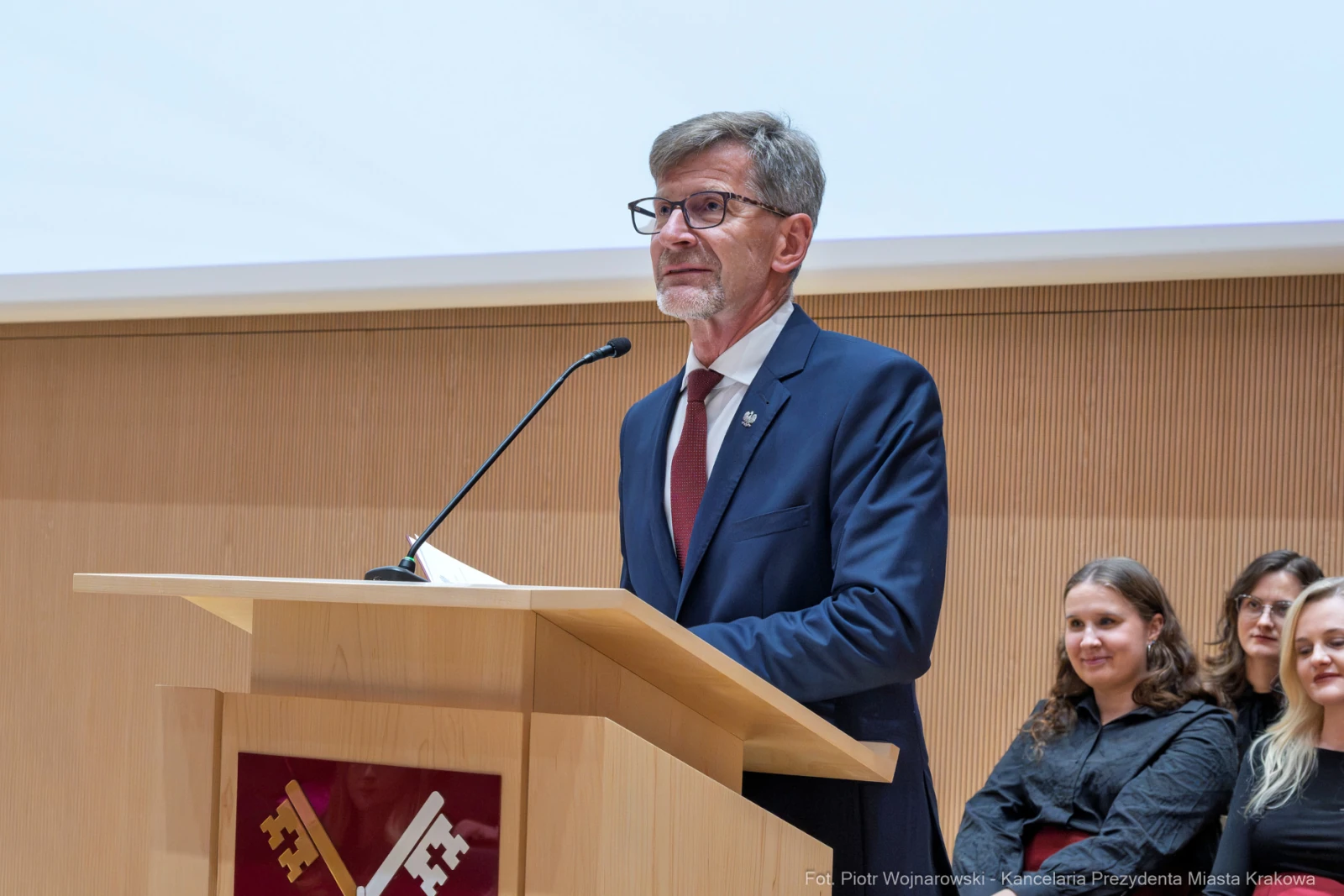 Mężczyzna w garniturze przemawia z mównicy, w tle siedzą słuchacze.  Autor: Piotr Wojnarowski