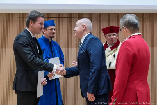 Uroczystość wręczenia dyplomów z gratulacjami i uściskiem dłoni.