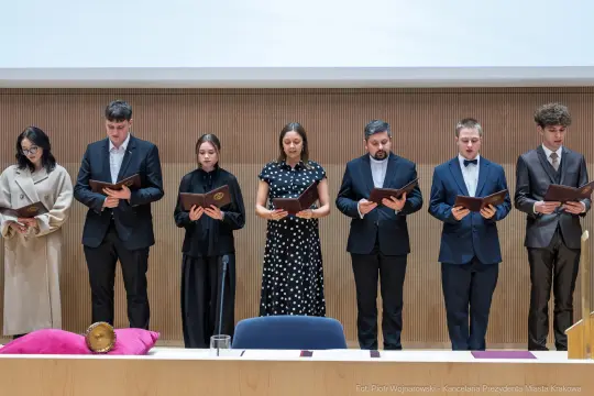 Ceremonia składania przysięgi przez grupę ludzi w formalnych strojach.