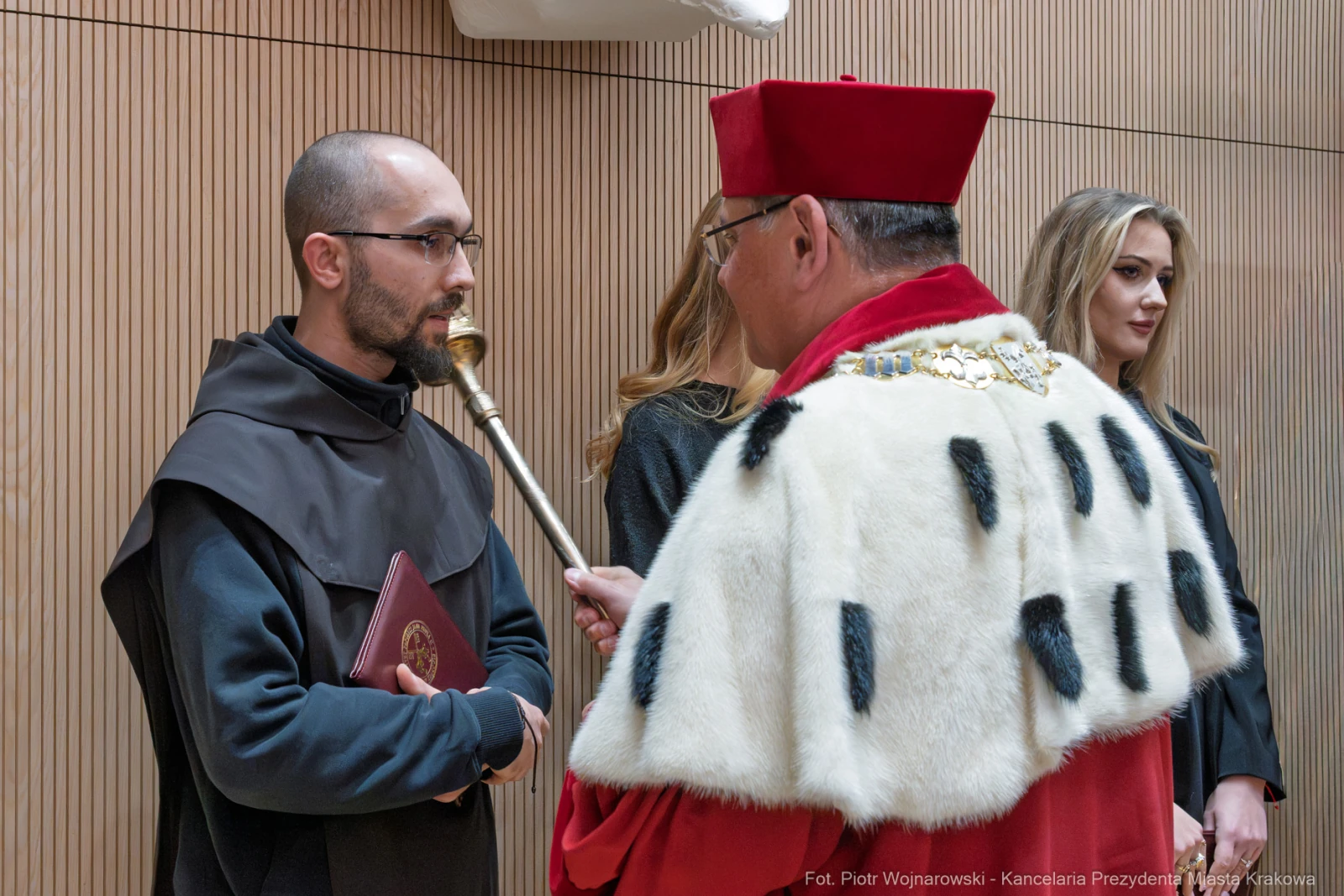 Ceremonia akademicka z udziałem mężczyzny w habicie i dostojnika w czerwonym stroju.  Autor: Piotr Wojnarowski