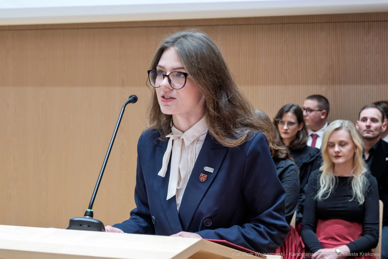 Młoda kobieta przemawia z mównicy, w tle widoczni słuchacze.  Autor: Piotr Wojnarowski