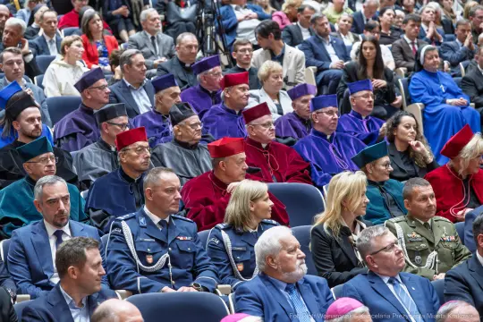 Uczestnicy ceremonii w tradycyjnych strojach akademickich i mundurach.