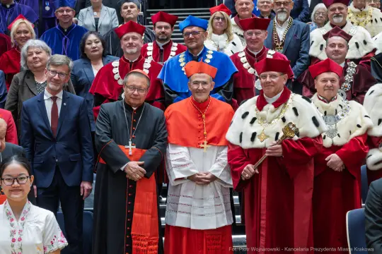 Grupa osób w strojach akademickich i duchownych, w tym kardynałowie i przedstawiciele uczelni.