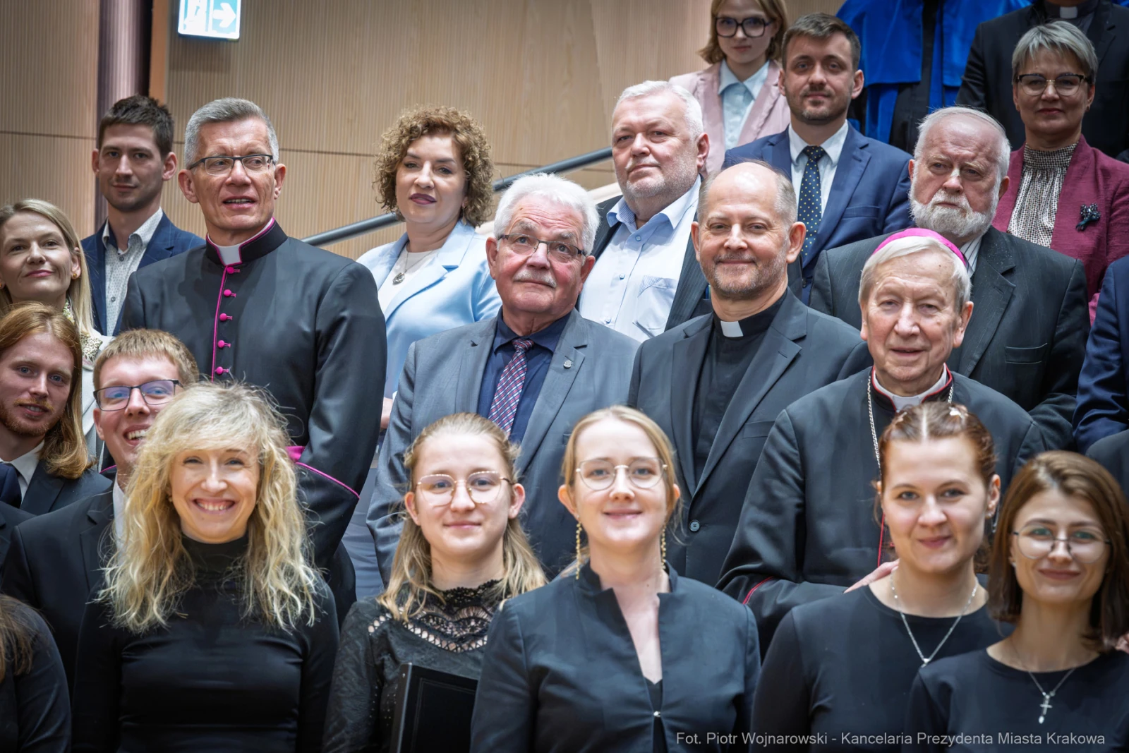 Grupa ludzi w formalnych strojach, w tym duchowni, na tle schodów w budynku.  Autor: Piotr Wojnarowski
