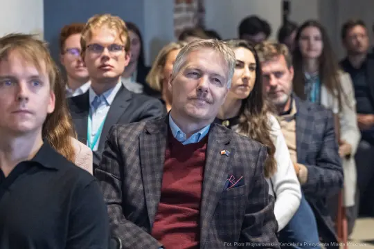 Grupa ludzi na konferencji, skupionych na prelekcji.
