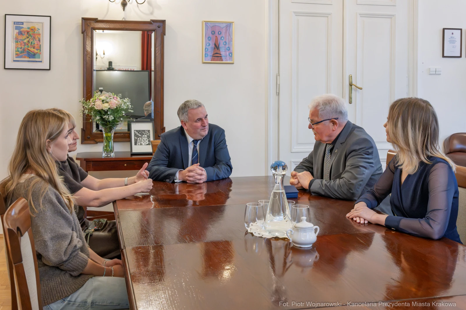 Spotkanie czterech osób przy stole w biurze, w tle kwiaty i obrazy na ścianach.  Autor: Piotr Wojnarowski