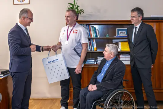 Wręczenie kalendarza przez prezydenta Krakowa medalistowi paraolimpijskiemu.