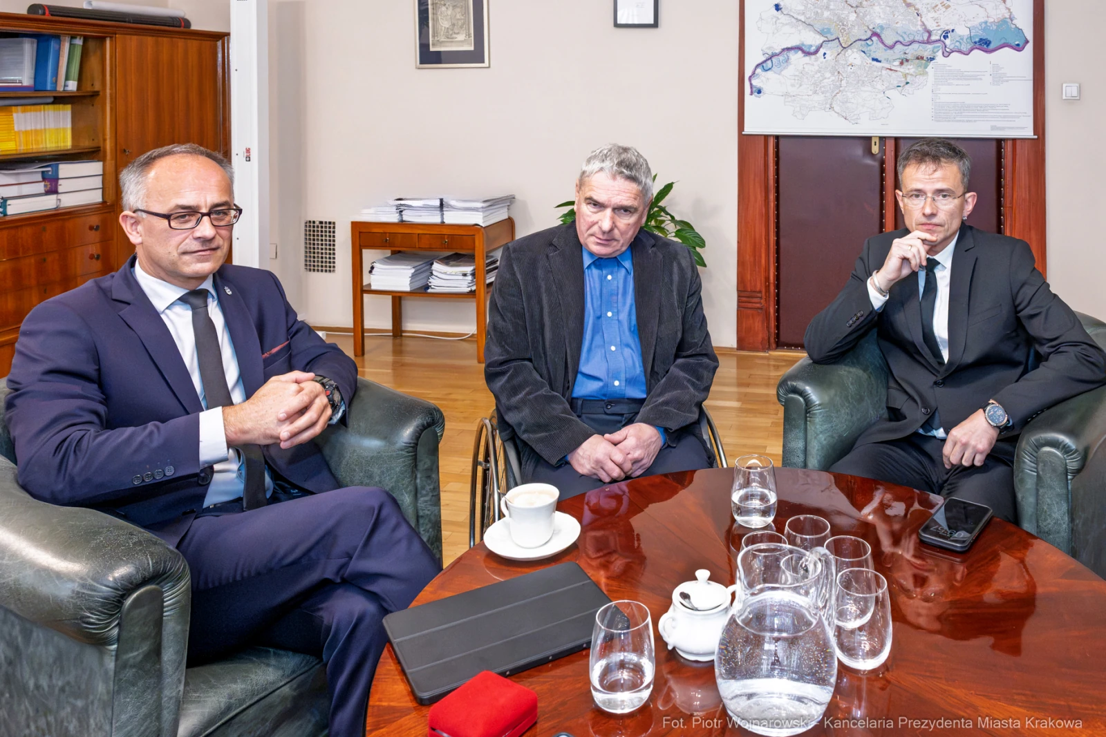 Trzech mężczyzn w garniturach siedzi w biurze, na stole filiżanki i dokumenty.  Autor: Piotr Wojnarowski