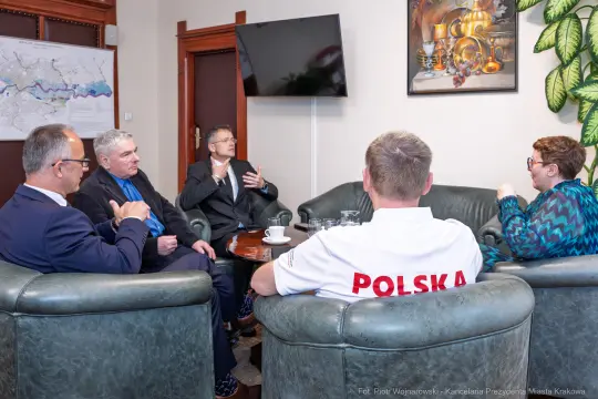 Spotkanie pięciu mężczyzn i jednej kobiety w biurze, dyskutują nad ważnymi sprawami.