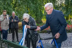 Uroczystość przecięcia wstęgi przez dwie osoby w parku.