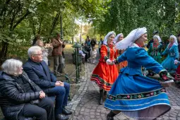 Tradycyjny taniec w kolorowych strojach ludowych, widownia obserwująca występ.
