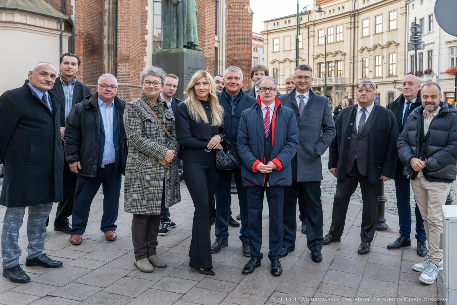 Grupa ludzi w formalnych strojach na tle historycznej architektury.  Autor: Piotr Wojnarowski