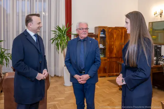 Spotkanie trzech osób w biurze, w tle meble i rośliny.
