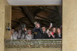 Muzyk grający na trąbce, otoczony przez tłum ludzi z aparatami i telefonami.