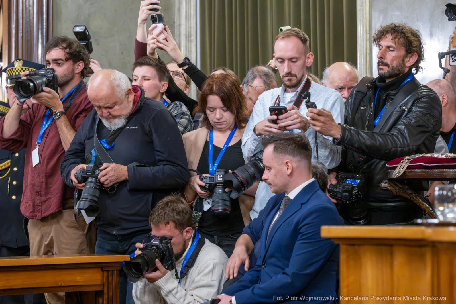 Grupa dziennikarzy i fotografów podczas wydarzenia, niektórzy z aparatami, inni z telefonami.  Autor: Piotr Wojnarowski
