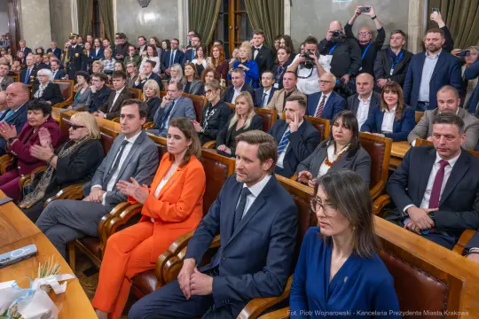 Spotkanie w sali obrad z uczestnikami i gośćmi, aplauz oraz różnorodne reakcje.