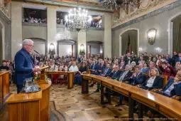 Wystąpienie mężczyzny przed zgromadzonymi gośćmi w eleganckiej sali.