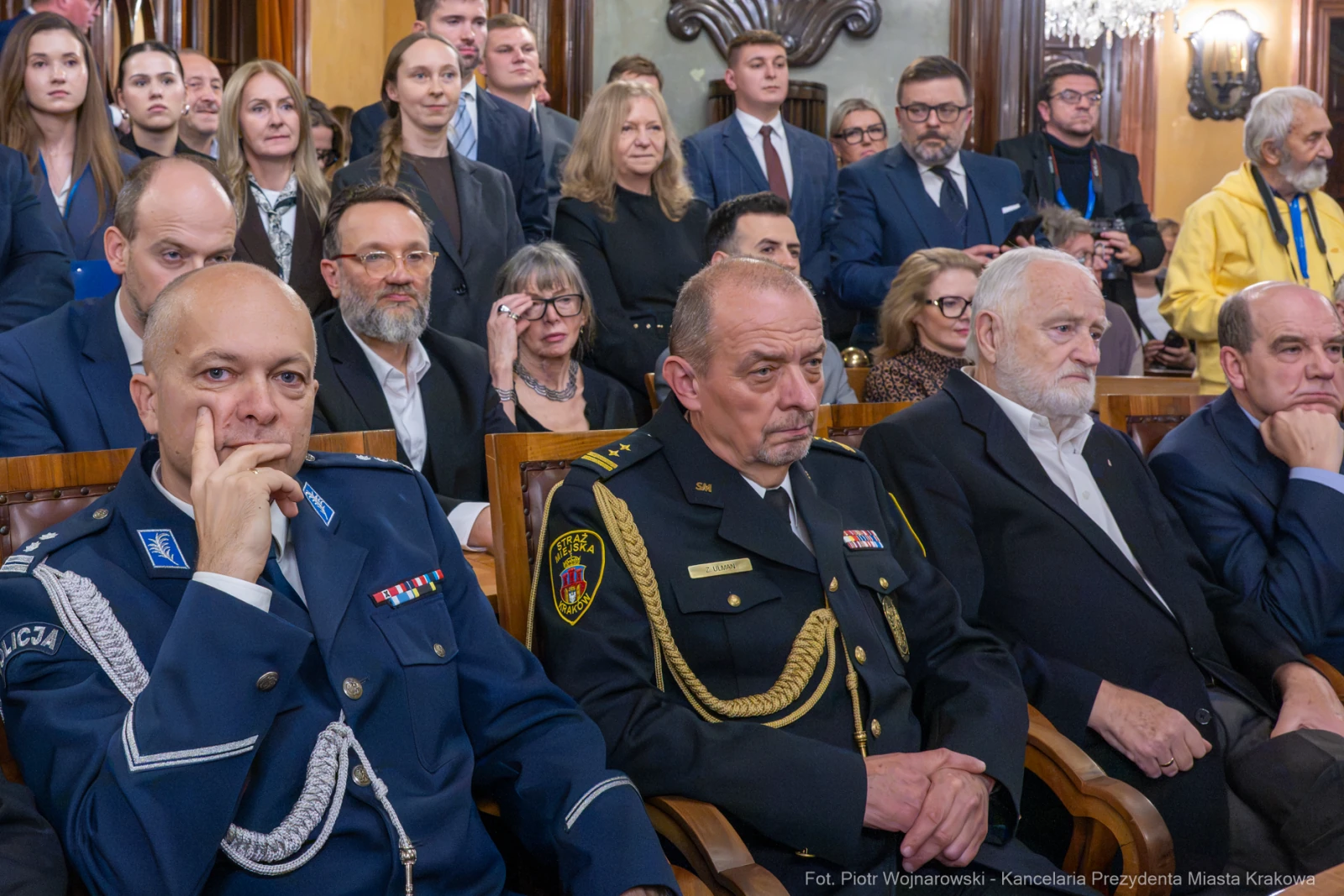 Grupa osób w formalnych strojach, siedzących w sali, z poważnymi wyrazami twarzy.  Autor: Piotr Wojnarowski