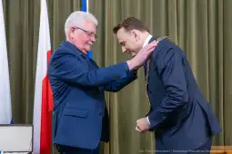 Ceremonia wręczenia odznaczenia przez jednego mężczyznę drugiemu.