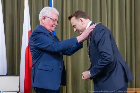 Ceremonia wręczenia odznaczenia przez jednego mężczyznę drugiemu.